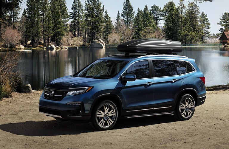 left side view of blue honda pilot by water