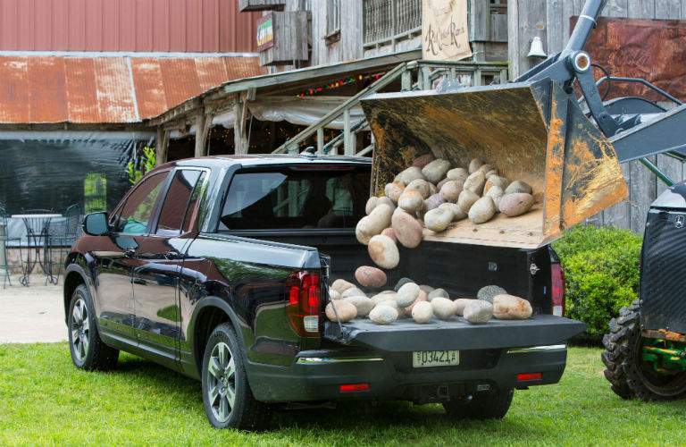 A photo of field stones being dropped into the back of a 2018 Ridgeline.