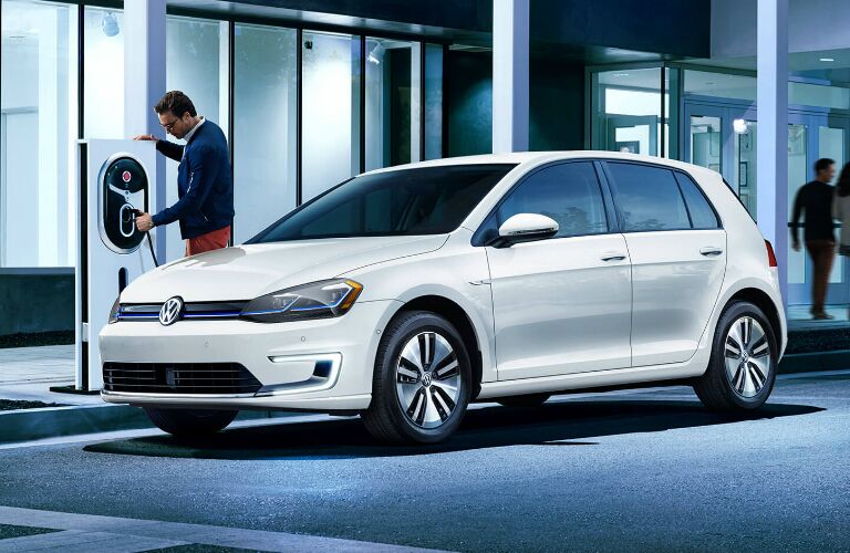 A man charging a white 2019 Volkswagen e-Golf