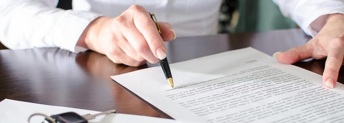 Close on hands of someone signing car loan or lease