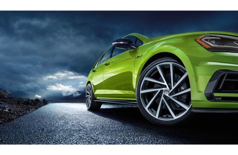 2019 Volkswagen Golf R exterior low shot with viper green paint color at night with clouds in the dark sky