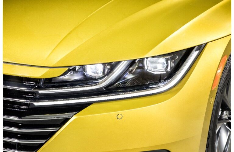 exterior closeup shot of 2019 Volkswagen Arteon LED headlight design with yellow body paint color