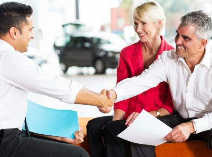 Couple Signing Paperwork at Dealership