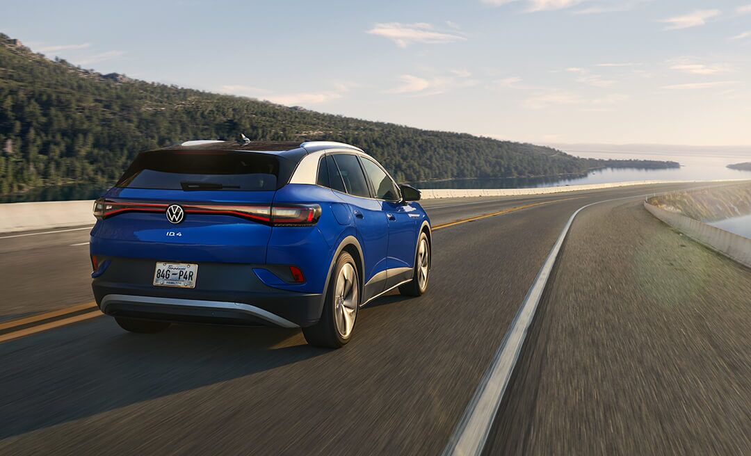 A wide shot of an ID.4 in Dusk Blue Metallic driving along an open highway.