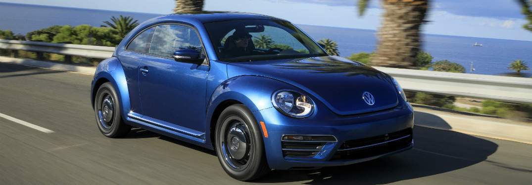 blue 2018 volkswagen beetle driving on coastal highway