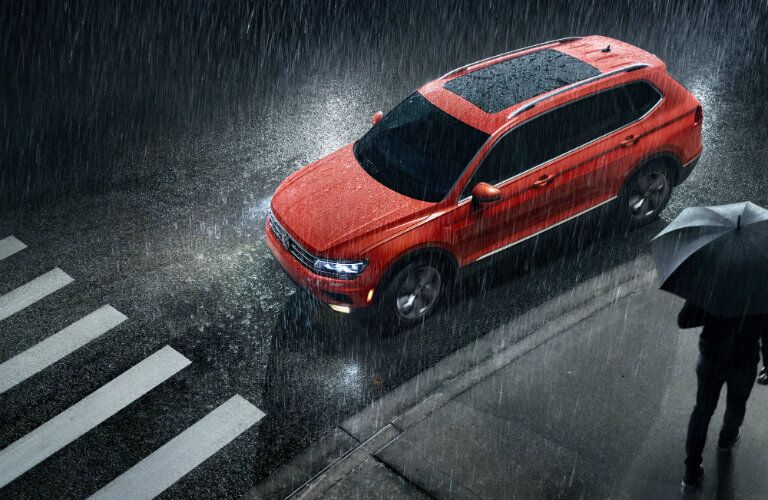 2019 Volkswagen Tiguan exterior overhead shot with red color paint job stop at a crosswalk during a rain shower with headlights on