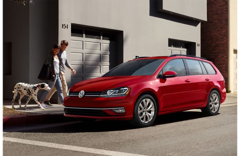 red Volkswagen Golf SportWagen by a dog