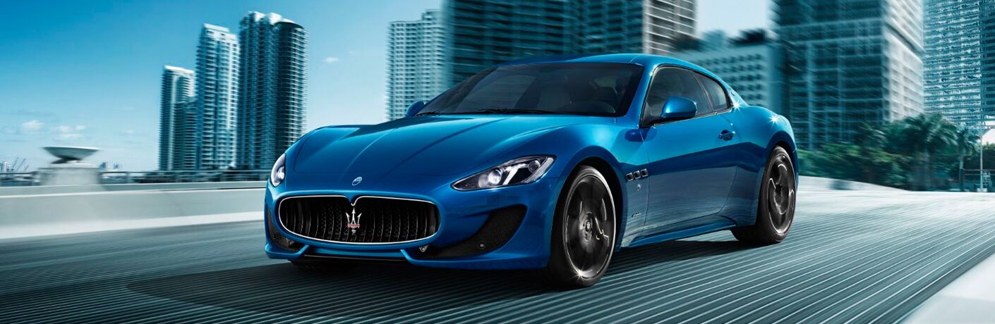 Blue 2017 Maserati GranTurismo on a City Freeway with a City Skyline in the Background
