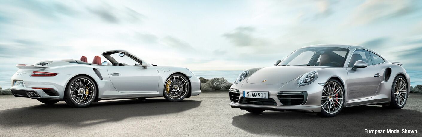 White Convertible and Silver Coupe 2018 Porsche 911 Turbo Next to the Water