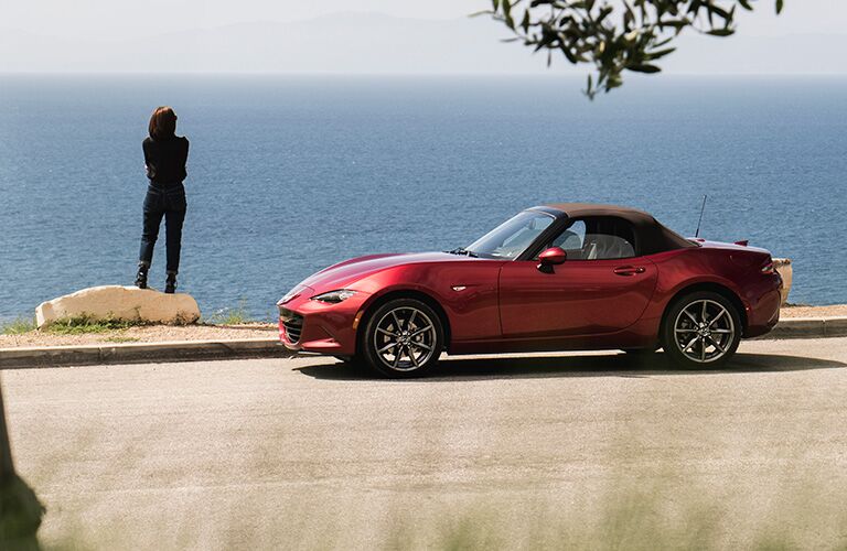 Red 2019 Mazda MX-5 Miata Side Exterior with Brown Soft Top Next to Water