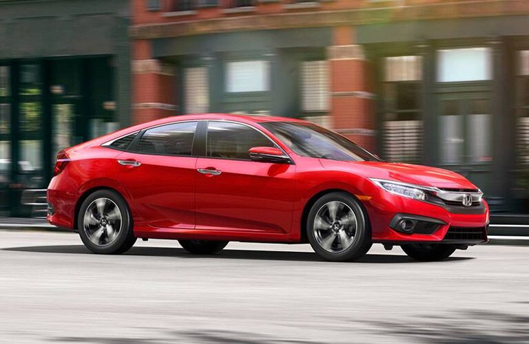 Red Honda Civic cruising along a city street.