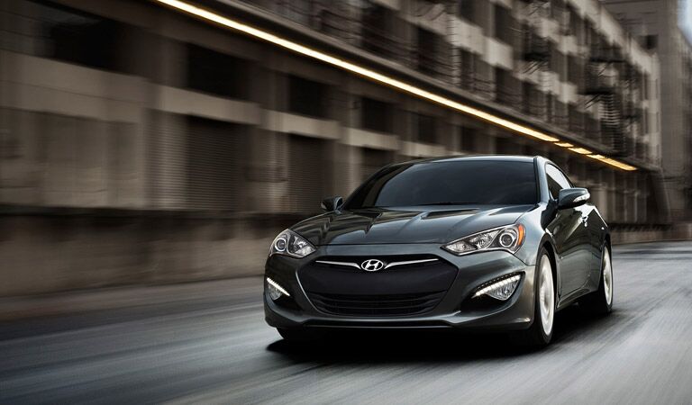 2016 Hyundai Genesis Coupe driving fast past high buildings