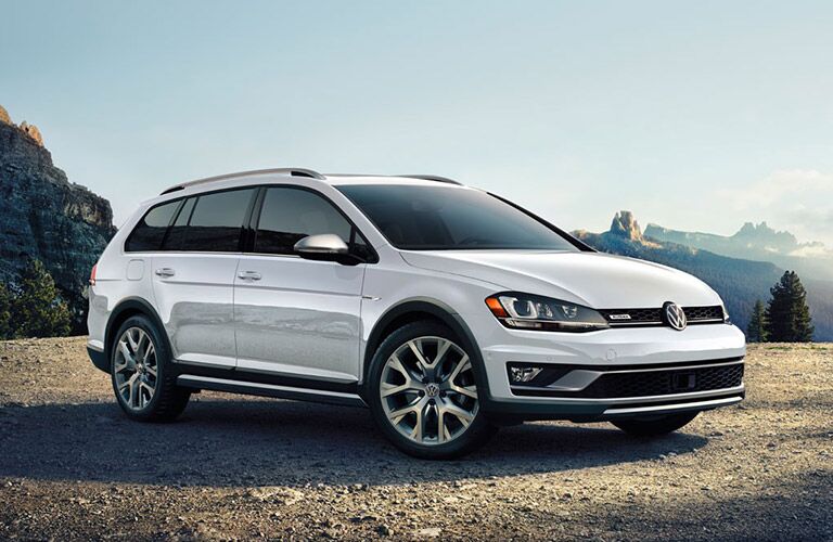 white Volkswagen Golf Alltrack parked by mountains and wide open spaces