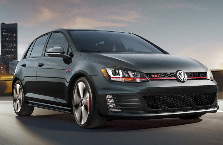 black Volkswagen Golf GTI driving across bridge at dusk