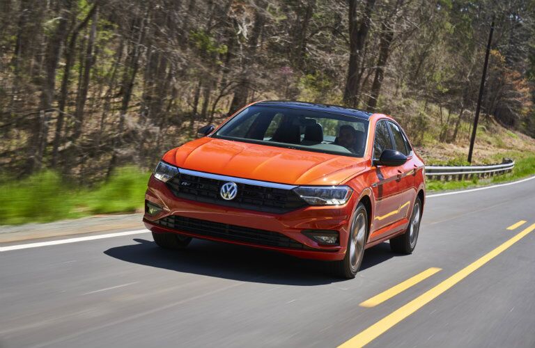Orange-colored 2019 Volkswagen Jetta cruising on a country road