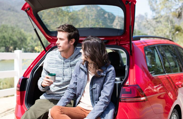 A man and woman sitting in the open hatch of the 2019 VW Golf Sportwagen
