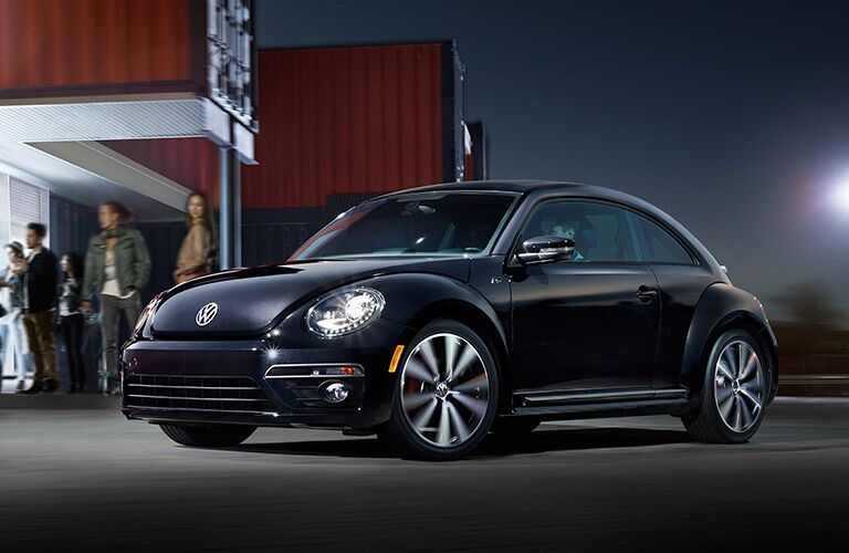 Black Volkswagen Beetle draws admiring looks outside a trendy club.