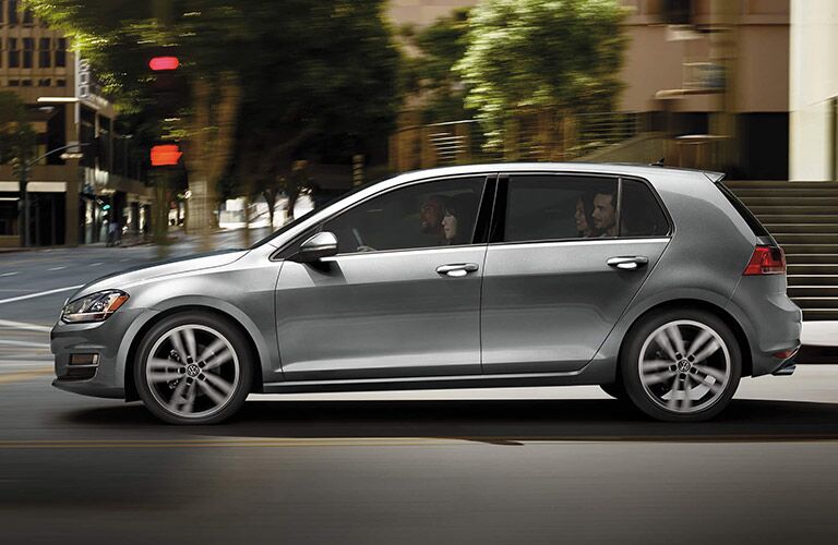 Silver Volkswagen Golf ambles through a city loaded comfortable with four occupants.