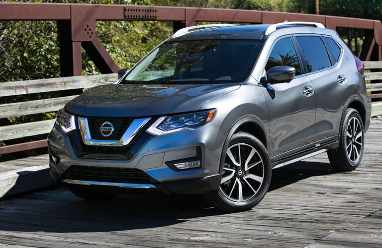 silver Nissan Rogue crossing an old wooden bridge