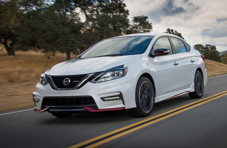 white Nissan Sentra with red exterior trim on country highway