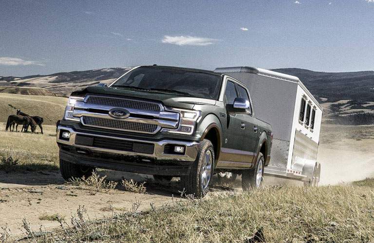 dark 2018 Ford F-150 towing a white trailer