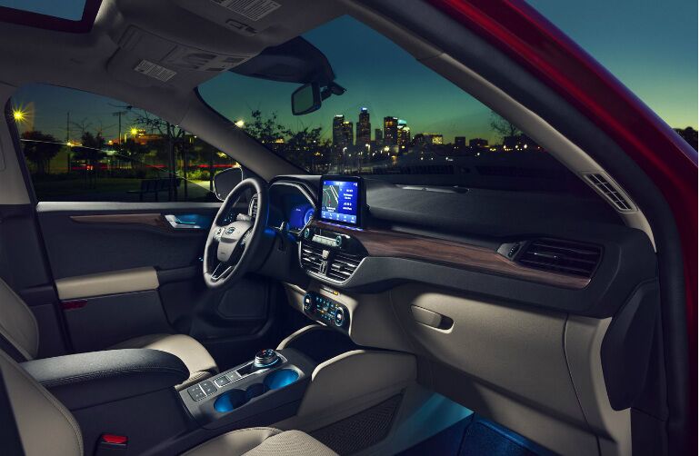 Interior front seat of the 2020 Ford Escape. Through the windows a city skyline is visible against the late-evening sky.