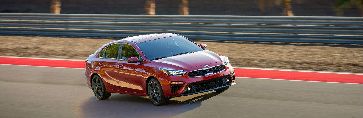 exterior shot of red kia forte driving on track