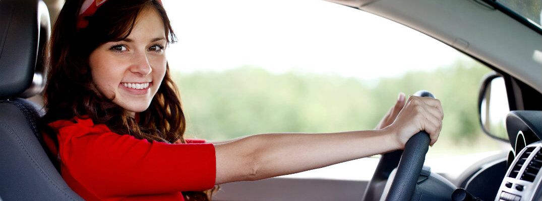 Woman in a red dress behind the wheel of a used vehicle