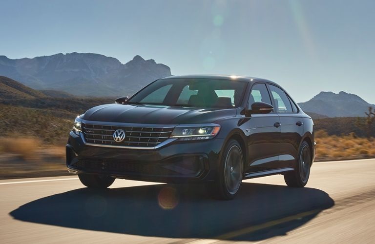 2022 VW Passat in Tourmaline Blue Metallic driving along highway with mountains in the background