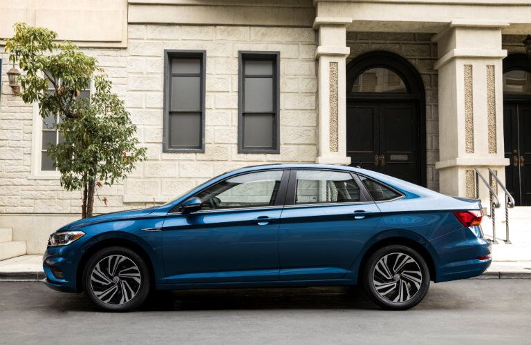 2019 Volkswagen Jetta exterior side shot length blue paint parked next to a fancy house