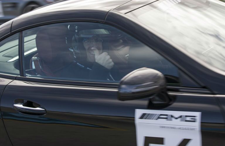 A man giving a thumb up inside an AMG academy car