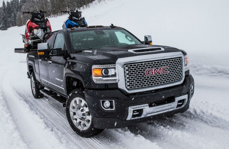2018 GMC Sierra 2500HD Denali driving on snow hauling snowmobiles