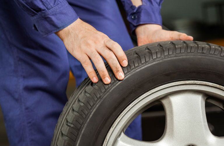 Technician Inspecting Tire in Blue Jumpsuit