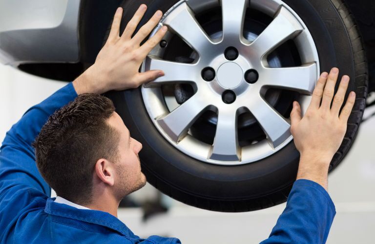 Technician Facing Tire Adjusting Alignment