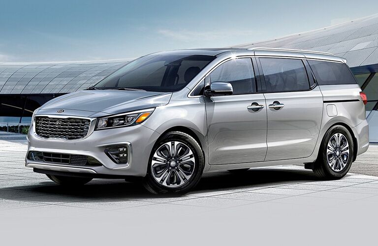 Silver 2020 Kia Sedona parked in front a large modernistic building