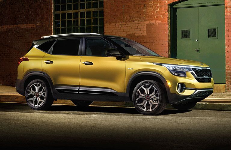 Yellow 2021 Kia Seltos parked next to a brick building
