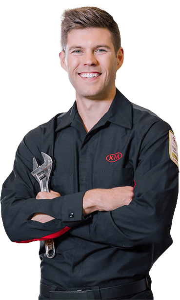 Smiling mechanic with arms crossed holds a wrench.