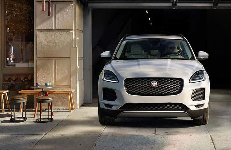 front view of the 2018 Jaguar E-PACE driving out a parking garage near a bistro