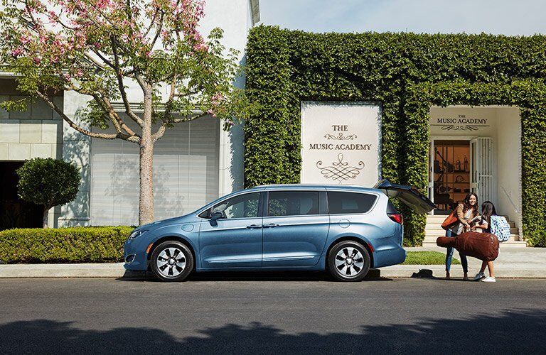 side view of the 2017 Chrysler Pacifica Hybrid in front of a music shop
