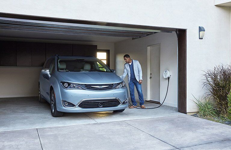 2017 Chrysler Pacifica Hybrid charging in a garage, an owner plugging it in