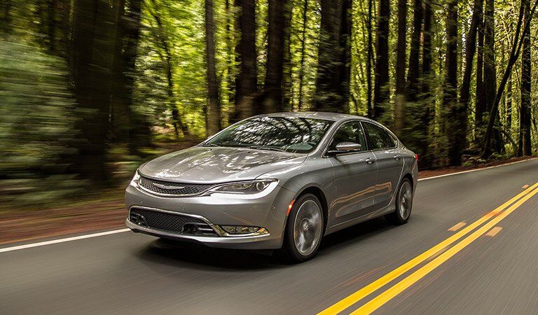 Chrysler 200 driving on a road through the woods