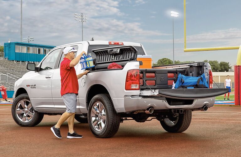 white 2018 Ram 1500 loaded with tailgating materials, man using the RamBox