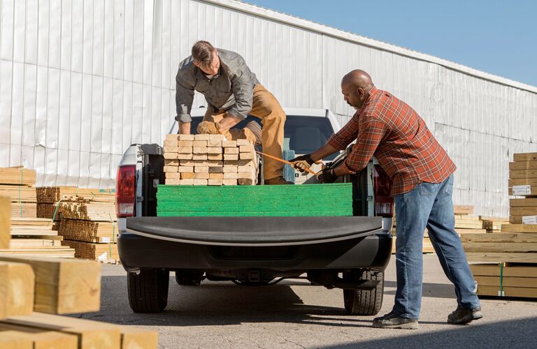lumber in the bed of the 2018 Ram 1500, two men loading
