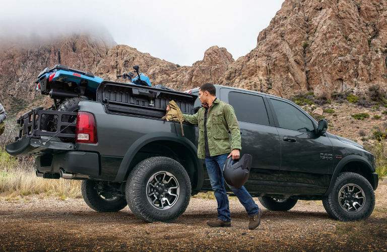 side view of a black 2018 Ram 1500 in front of cliffs loaded with a four-wheeler