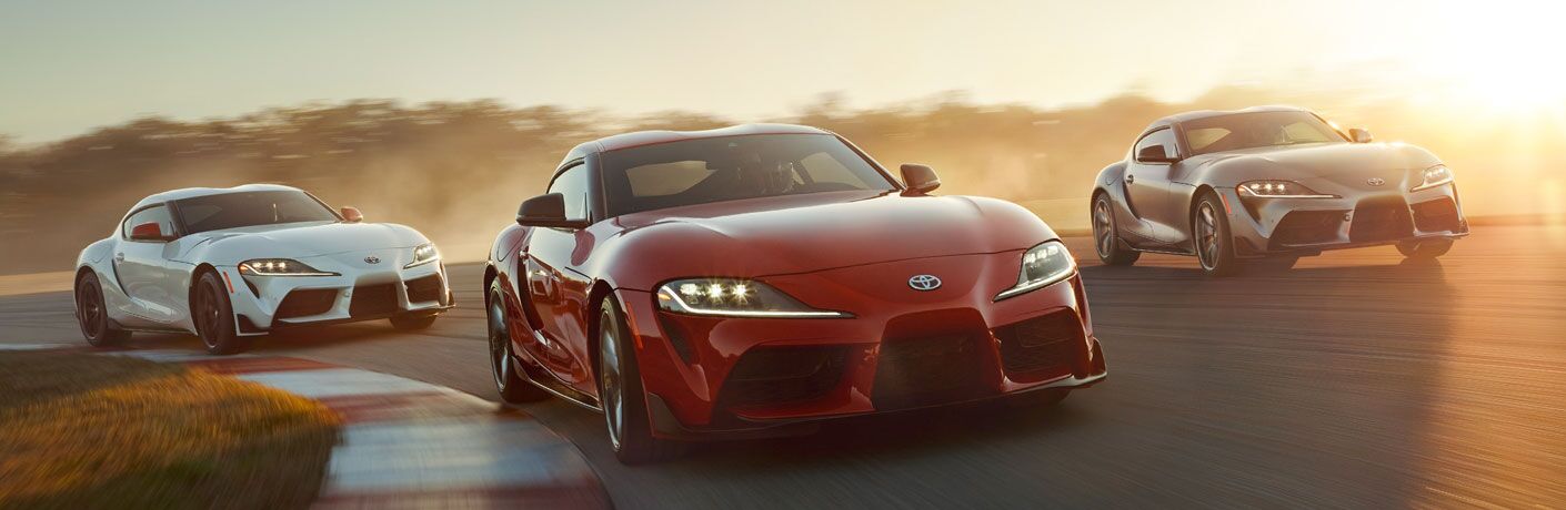 Three 2020 Toyota Supra models driving on a race track at dusk
