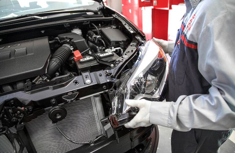Toyota service technician repairing a vehicle headlight