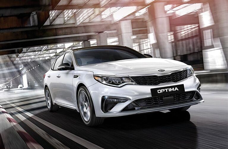 2019 Kia Optima driving down a road.