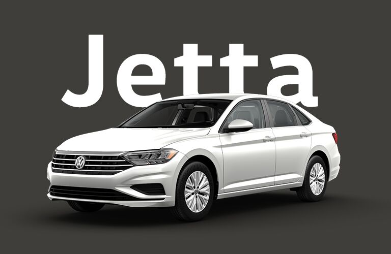 Silver Volkswagen Jetta in front of a black background and gigantic white text that reads, "Jetta."