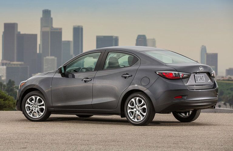View of gray 2016 Scion iA parked on pavement with city skyline in background