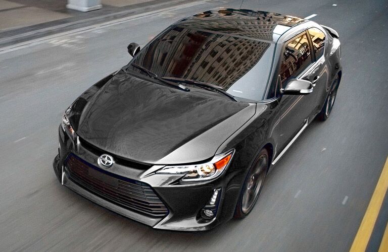 View of 2016 black Scion tC driving down a city street